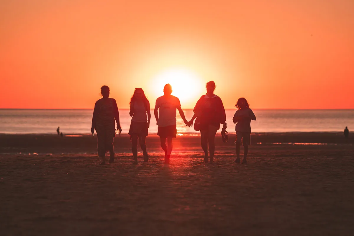 A group of friends walking together on a beach at sunset