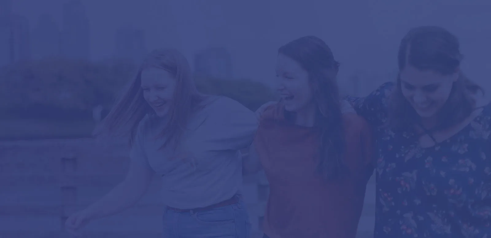 Three friends laughing together outdoors